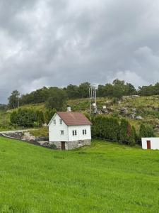 uma pequena casa branca num campo de relva em Hus med sentral beliggenhet em Tysvær