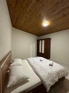 a bedroom with a large white bed with a wooden ceiling at Private apartment in Tbilisi City