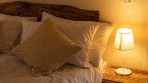 un letto con cuscini bianchi e un tavolo con una lampada di Al Castello di Elcito a San Severino Marche