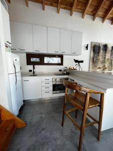 a kitchen with white cabinets and a wooden chair at Casa Silente in San Carlos de Bariloche