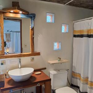 y baño con lavabo, aseo y espejo. en Cabañas Bahia Serena, en Punta del Diablo