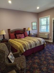 um quarto com uma cama, uma cadeira e uma janela em Hearthstone Elegant Lodge em Kamiah