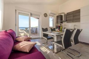 a living room with a purple couch and a table with chairs at Apartments Katic in Ražanj