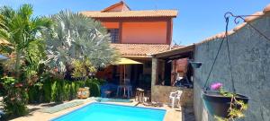 a villa with a swimming pool in front of a house at Casa do Edi in Maricá