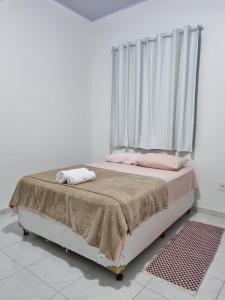 a bedroom with a bed with pink pillows and a window at Pousada Talismã in Barreirinhas