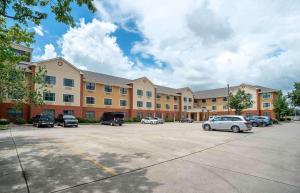 肯纳Extended Stay America Select Suites - New Orleans - Airport的一座大楼，停车场里停满了汽车