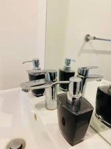 a bathroom sink with three faucets on it at Yolé Apartment - City 101 in Windhoek