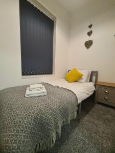 ein Schlafzimmer mit einem Bett mit gelbem Kissen und einem Fenster in der Unterkunft Tower Views 2 Bedroom House with Private Parking in Blackpool