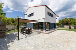 una casa con un padiglione con tavolo e sedie di VILLA VERONIQ z bazenom & jacuzzi a Soline