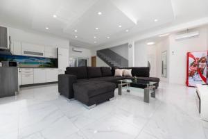 un soggiorno con un divano nero e una cucina di VILLA VERONIQ z bazenom & jacuzzi a Soline