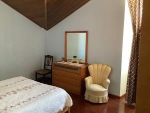 ein Schlafzimmer mit einer Kommode, einem Spiegel und einem Bett in der Unterkunft Casa das Camélias in Gouveia