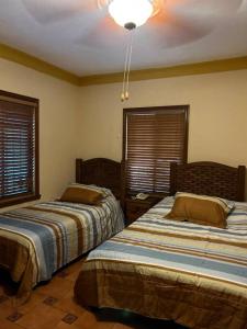 two beds in a room with two windows at Hermosa casa estilo Mexicano in Monterrey