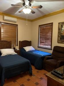 a bedroom with two beds and a couch and a ceiling fan at Hermosa casa estilo Mexicano in Monterrey