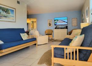 ein Wohnzimmer mit blauen Sofas und einem Flachbild-TV in der Unterkunft Hacienda del Sol II - 103 in New Smyrna Beach