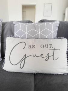 a pillow that says be our guest on a couch at 2 Bed Terrace 5 Minutes from Anfield Stadium in Liverpool