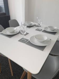 a white table with plates and wine glasses on it at 2 Bed Terrace 5 Minutes from Anfield Stadium in Liverpool