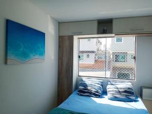 een slaapkamer met een bed en een raam bij Sobrado Carpe Diem Palmeiras, 450 m da praia, 2 suítes com ar, 2 vagas, check-in 24h, churrasqueira, 20 min do Beto Carrero in Piçarras