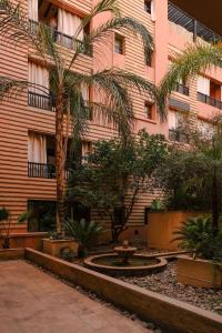 un edificio con un patio con palmeras y una fuente en Magnifiaue appart en Marrakech