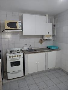 a kitchen with a white stove and a microwave at La juramento in San Miguel de Tucumán