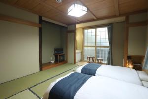 1 dormitorio con 2 camas y ventana grande en Oyado Uchidaya, en Nozawa Onsen