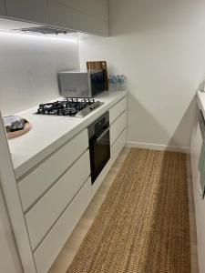 a kitchen with a stove and white cabinets and a rug at Beautiful Ocean View Apartment Signature Broadbeach in Gold Coast