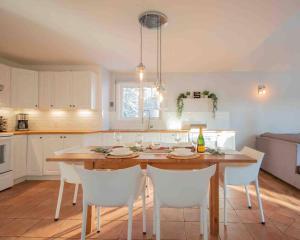 a kitchen with a wooden table and white chairs at Chalet BIA - Le Petit Chaleureux in Ham Nord