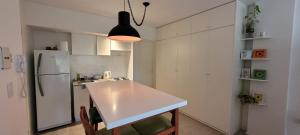 une cuisine avec un réfrigérateur blanc et une table blanche dans l'établissement Departamento amoblado en centro de Rosario, à Rosario 4 autres photos