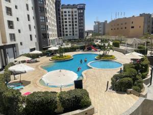 a large pool with people in it with umbrellas at Classy 2 floors with 2pools in NC in Cairo