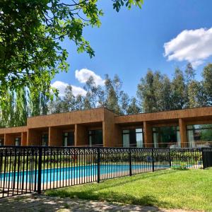 a building with a pool behind a fence at Parronales de Los Boldos in Santa Cruz
