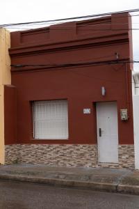 a red building with a white door and a window at Casa amueblada en centro de Minas, Lavalleja in Minas