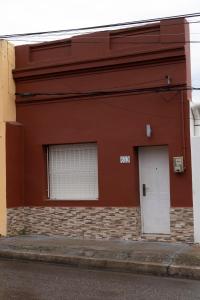 a red building with a white door and a window at Casa amueblada en centro de Minas, Lavalleja in Minas +2 photos