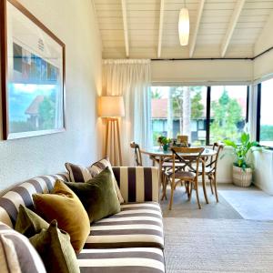 Emerald Inn on Takapuna Beach في أوكلاند: غرفة معيشة مع أريكة وطاولة
