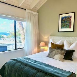 a bedroom with a bed and a large window at Emerald Inn on Takapuna Beach in Auckland