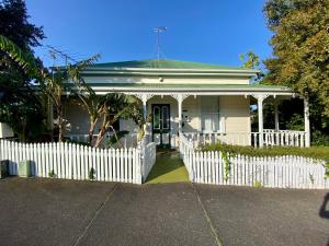 een wit hek voor een wit huis bij Quiet secret garden Sun-trap in Auckland