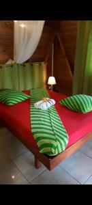 czerwone łóżko z zielonymi poduszkami i czerwoną prześcieradłem w obiekcie Fetay Jaune w mieście Baie-Mahault