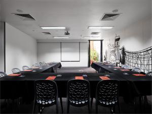a conference room with tables and chairs and a screen at Saint Kilda Beach Hotel - formerly Rydges St Kilda in Melbourne