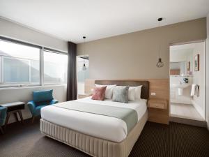 una camera d'albergo con letto e sedia blu di Saint Kilda Beach Hotel - formerly Rydges St Kilda a Melbourne