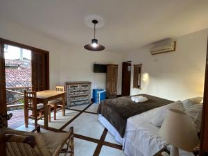 a bedroom with a bed and a table and a desk at Pousada Villa Nina in Ilhabela