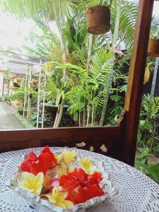 un plato de flores en una mesa frente a una ventana en Buratwangi Joglo House, en Kerobokan