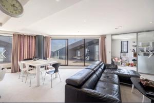 a living room with a black leather couch and a table at Apartment with Brilliant views in Auckland CBD in Auckland