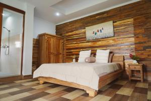 a bedroom with a wooden accent wall and a bed at Nyaman Villa Ubud - Gemütliche Wohnung in Reisfelder in Ubud