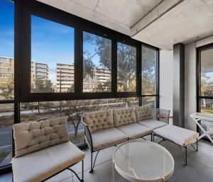 - un salon avec un canapé, une table et des fenêtres dans l'établissement Embark Luxe 2BR 2Bath Apartment in Lynham 1 Secure Carpark Wifi Canberra, à Canberra