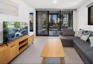 a living room with a couch and a flat screen tv at Embark Luxe 2BR 2Bath Apartment in Lynham 1 Secure Carpark Wifi Canberra in Canberra