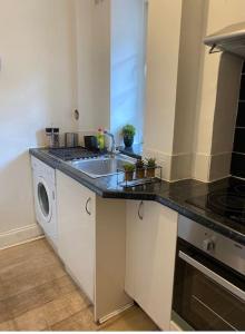 a kitchen with a sink and a washing machine at Cosy 1 Bed Flat in Central London with View of Shard in London