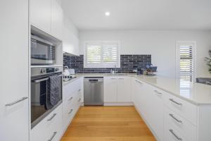 a white kitchen with white cabinets and a microwave at Port Macquarie Ocean Escape in Port Macquarie
