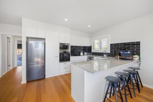 a kitchen with white cabinets and a stainless steel refrigerator at 'Beautiful View' close to Flynns Beach in Port Macquarie