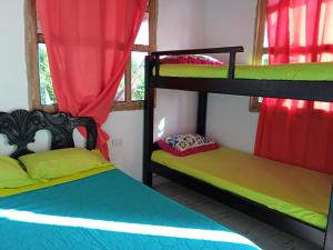 2 Etagenbetten in einem Zimmer mit roten Vorhängen in der Unterkunft Hospedaje Paula C in Calao