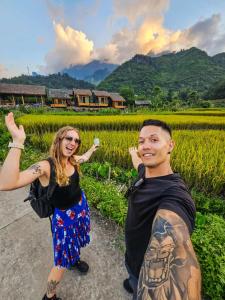 a man and a woman posing in front of a field at Chien's Lodge Du Gia in Làng Cac