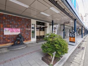 un edificio con una estatua y un arbusto delante de él en Hotel SIMIZU en Tokamachi