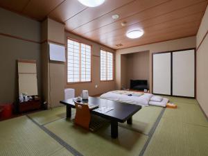 1 dormitorio con 1 cama, mesa y sillas en Hotel SIMIZU en Tokamachi